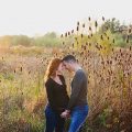 un couple de futurs parents dans un champ et la lumière du soleil couchant