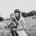 les mariés marchent dans un champ pendant leur séance photo