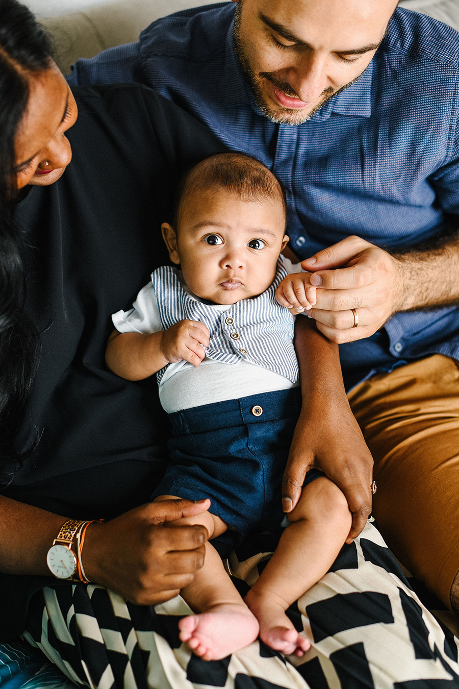 un petit garçon est assis sur les genoux de ses parents