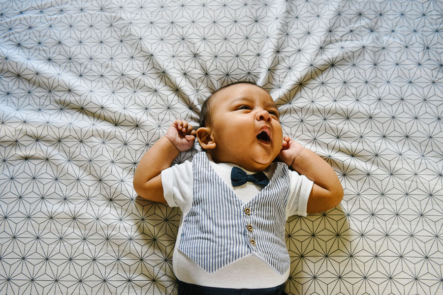 un bébé baille sur un lit